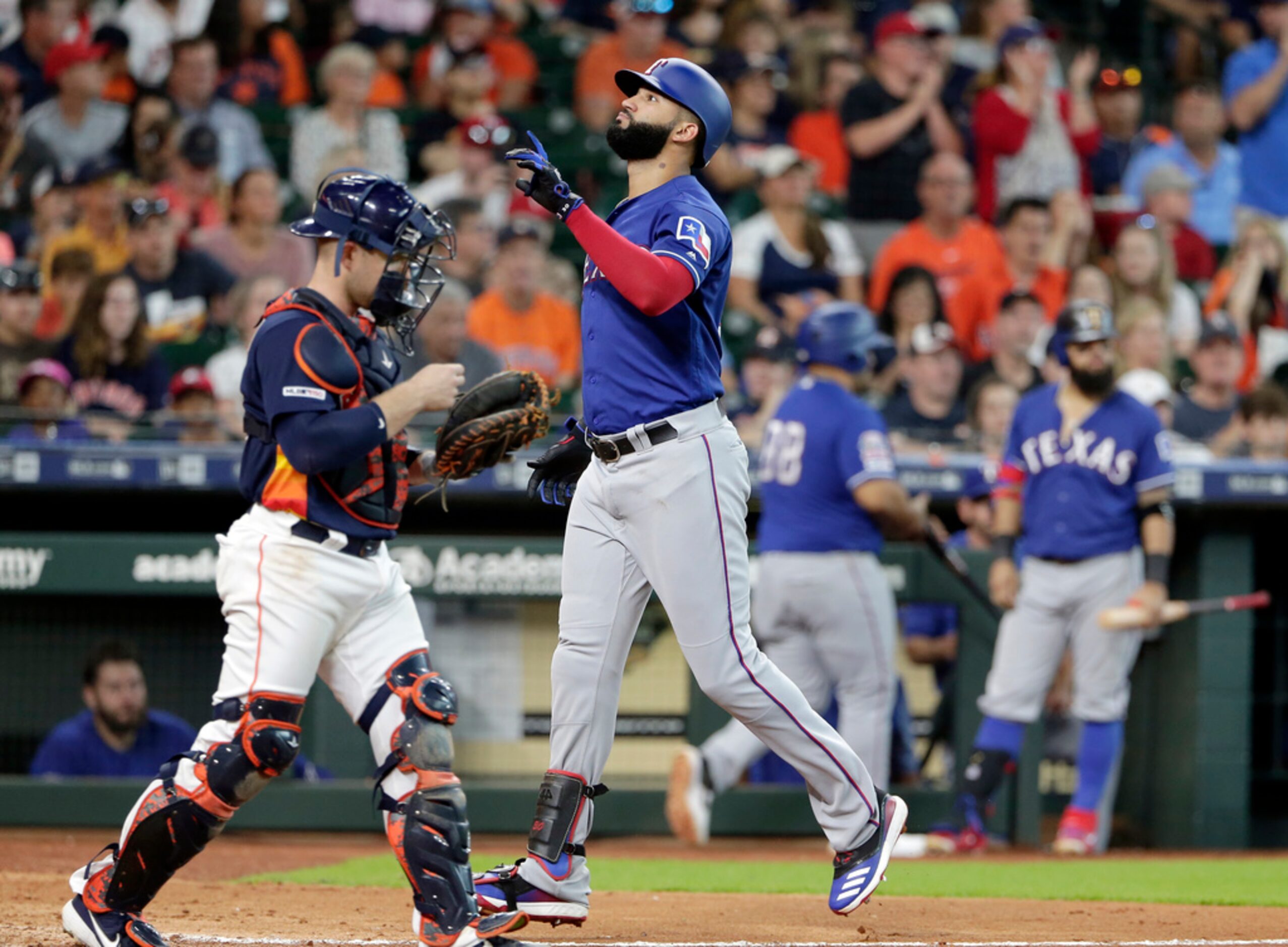 Texas Rangers' Nomar Mazara, front right, points up as he crosses the plate past Houston...