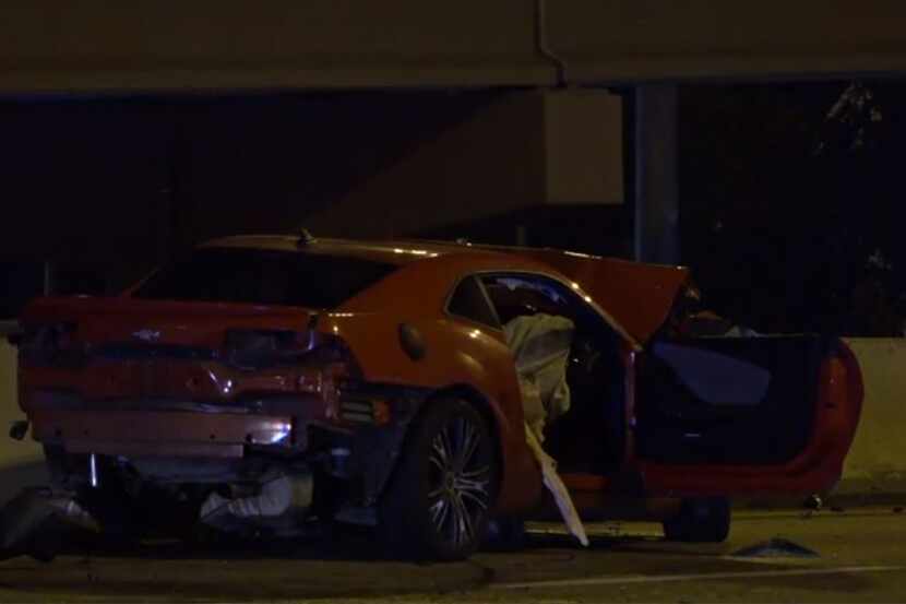 A wrecked Chevrolet Camaro lies along Interstate 35E near Royal Lane after it was involved...
