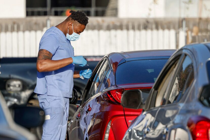 Physician Wes Edoso administers a COVID-19 test at a Texas Rapid Care testing site near...