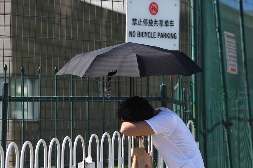 A man rests on the fence near the site of an explosion outside the US embassy in Beijing on...