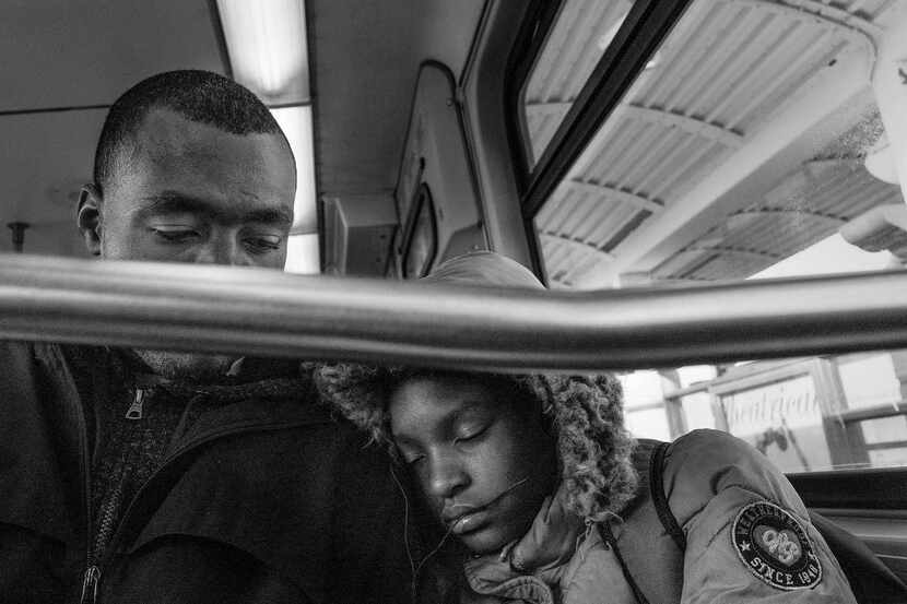 A black-and-white photo by Richard Sharum shows a sleepy black child and her father riding...