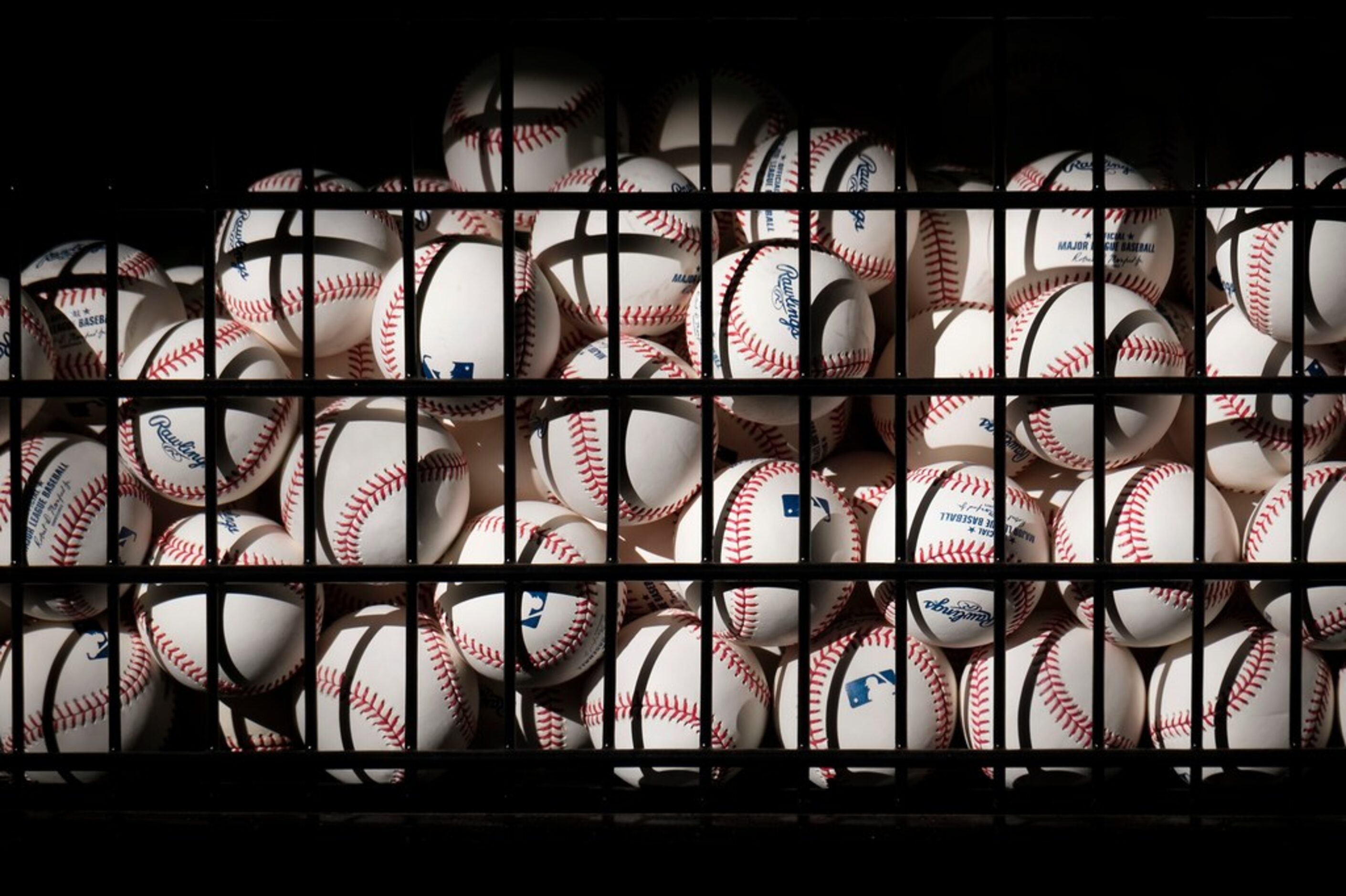 A basket of balls sits ready in the batting cages as Texas Rangers pitchers and catchers...