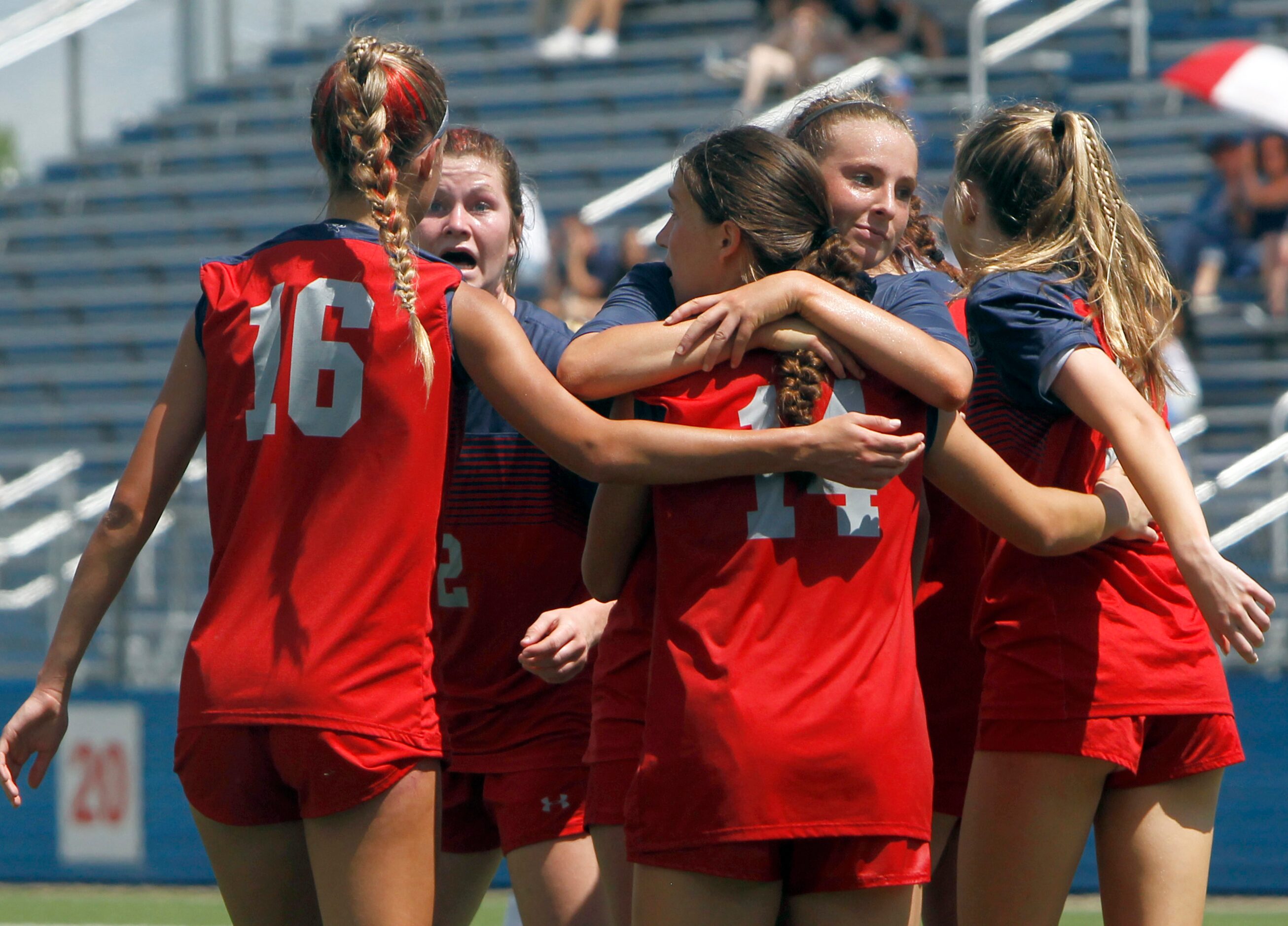 Grapevine midfielder Caroline Martin (15), center, hugs forward Theresa McCullough (14)...