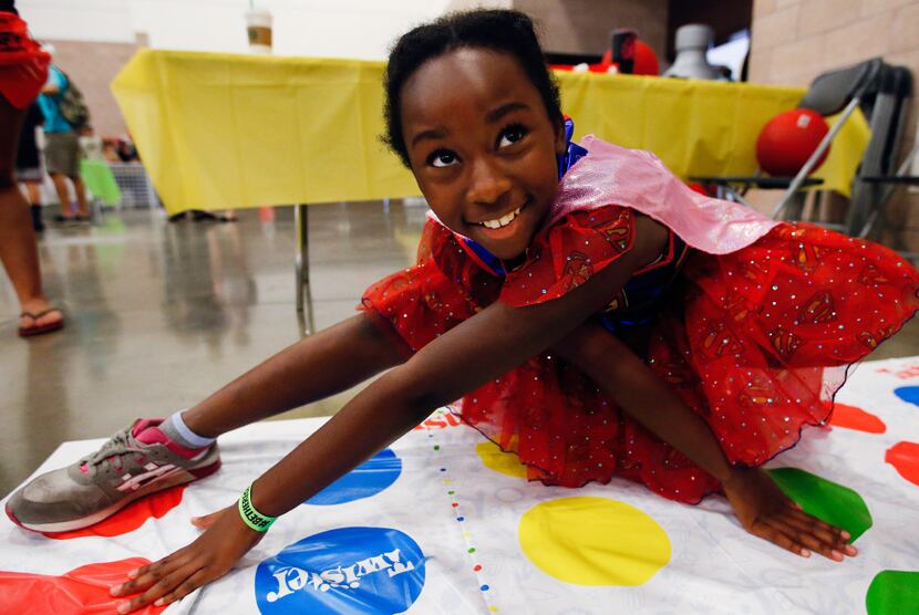 Lailah Burton, 10, plays twister with her mom during the Let's Play Gaming Expo at the...