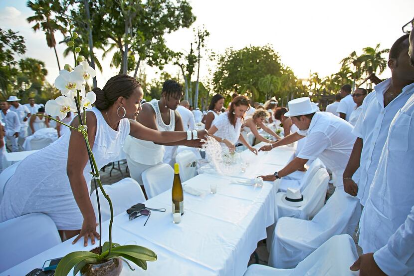 Enjoying a fabulous all-white picnic does take some work. Here, attendees set up their...
