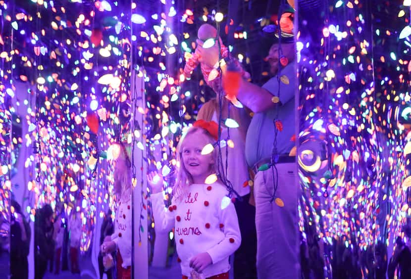 Charlotte Morrow, 5, laughs at her reflection in a hall of lights at holiday photo...