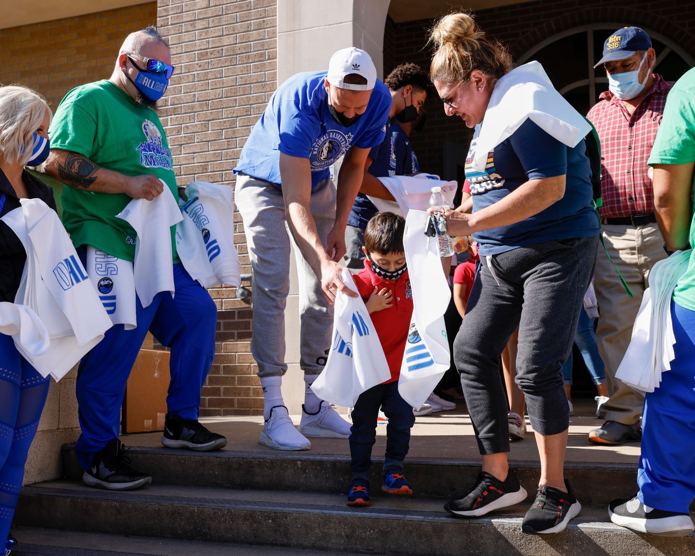 Dallas Mavericks center Kristaps Porzingis gives a Dallas Mavericks towel to a student after...