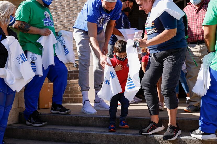 Dallas Mavericks center Kristaps Porzingis gives a Dallas Mavericks towel to a student after...