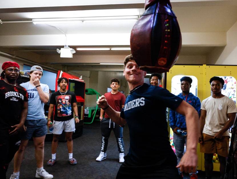 L.D. Bell High School football players watch Jon Rhiddlehoover punch a punching bag arcade...