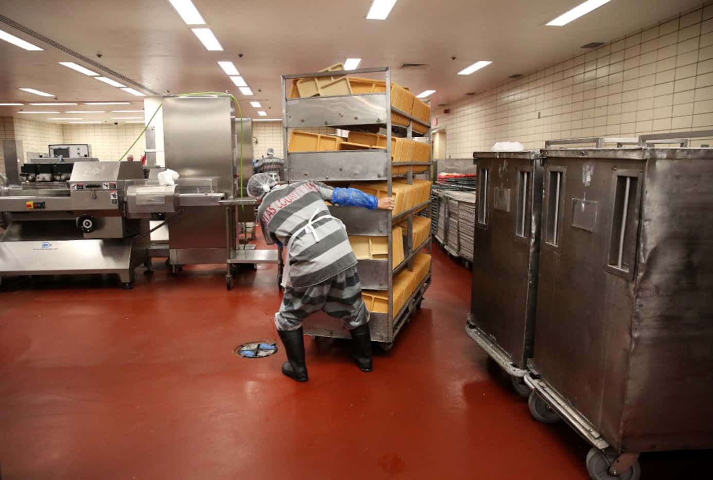An inmate moves a cart of trays for meal prep in the kitchen at the Lew Sterrett Justice...