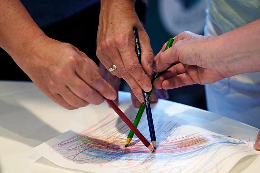 Teachers trace the lead line while sketching during a sensory motor therapy exercise at a...
