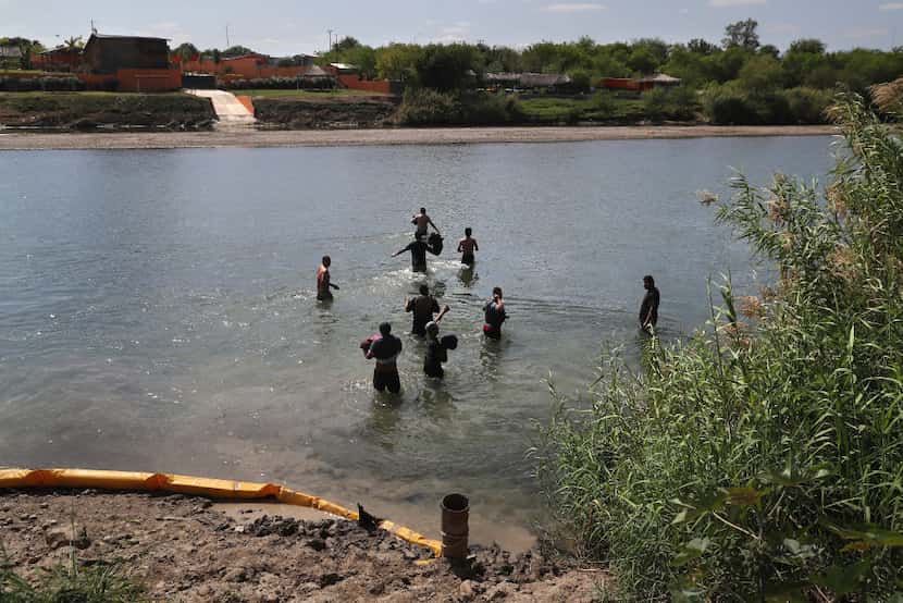 Unauthorized immigrants wade across the Rio Grande at the U.S.-Mexico border on March 14 in...