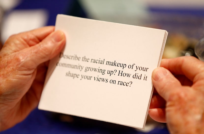 A participant reads a question about race at the dining table during the Together We Dine...