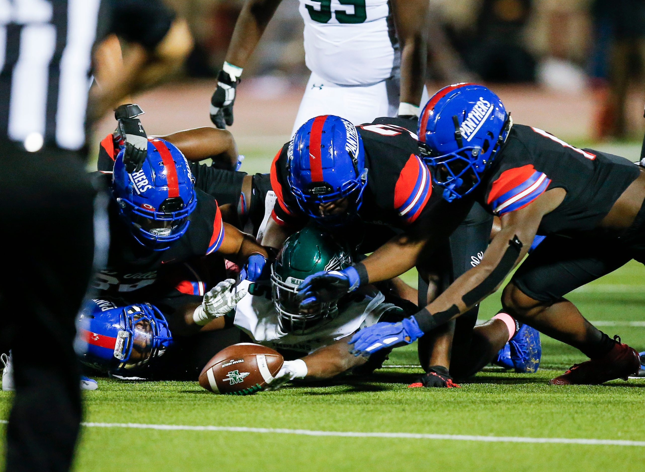 Waxahachie junior running back Jayden Becks, bottom center, fumbles the ball during the...