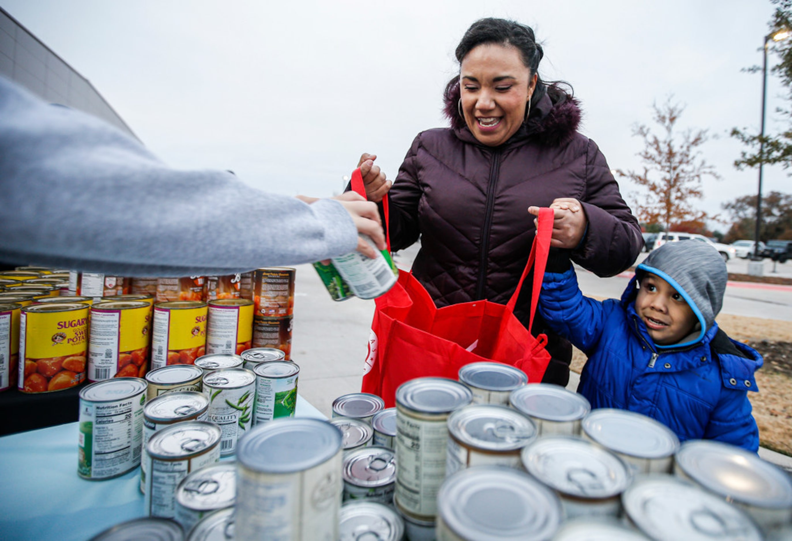 Nubia Quintero and her son Mateo Dominguez, 3, receive cans of green beans along with other...