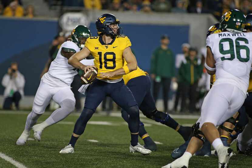 West Virginia quarterback JT Daniels (18) looks for a receiver during the first half of the...