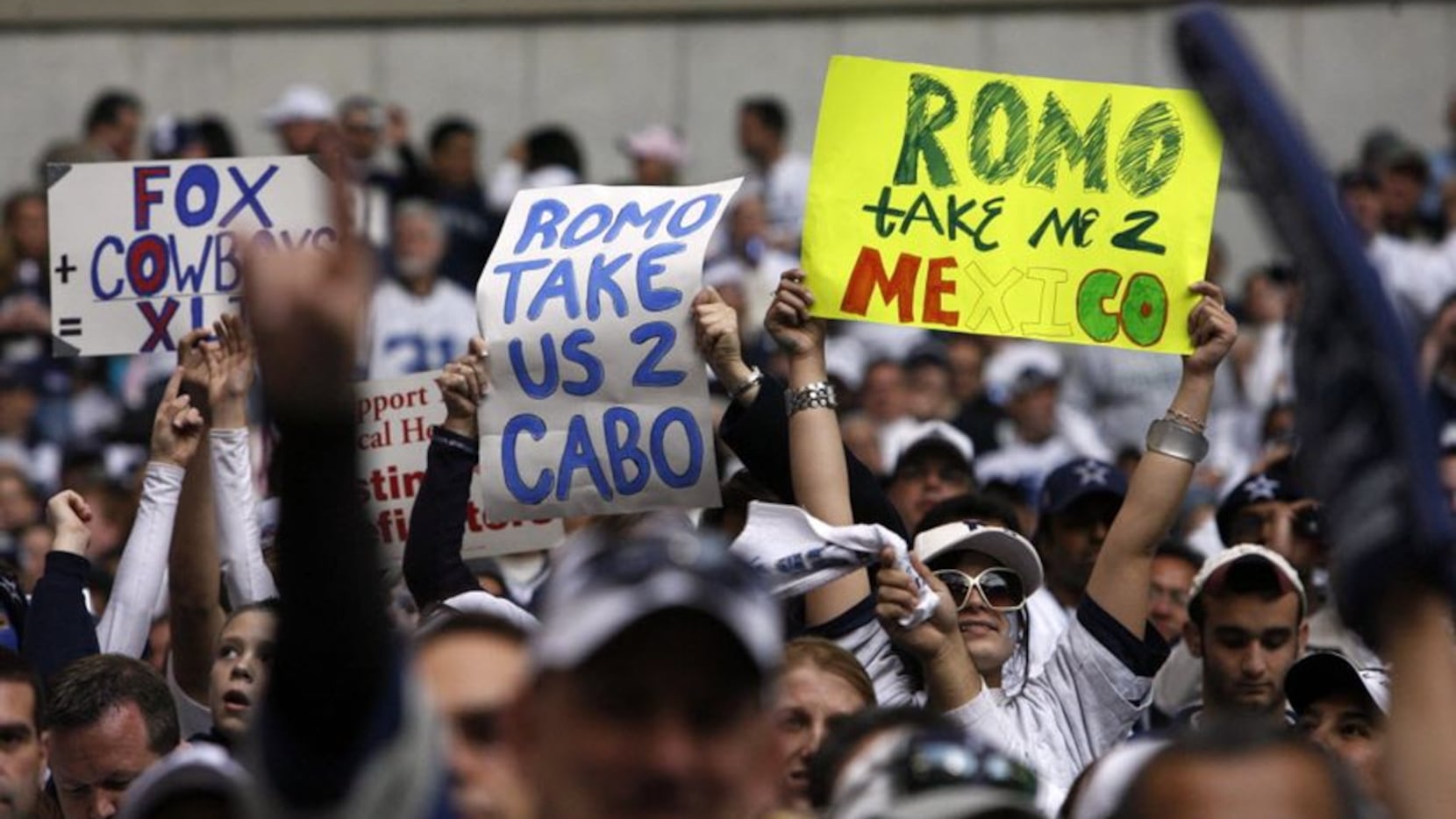 Fans hold signs supporting Tony Romo's bye-week trip to Mexico during the Cowboys'...