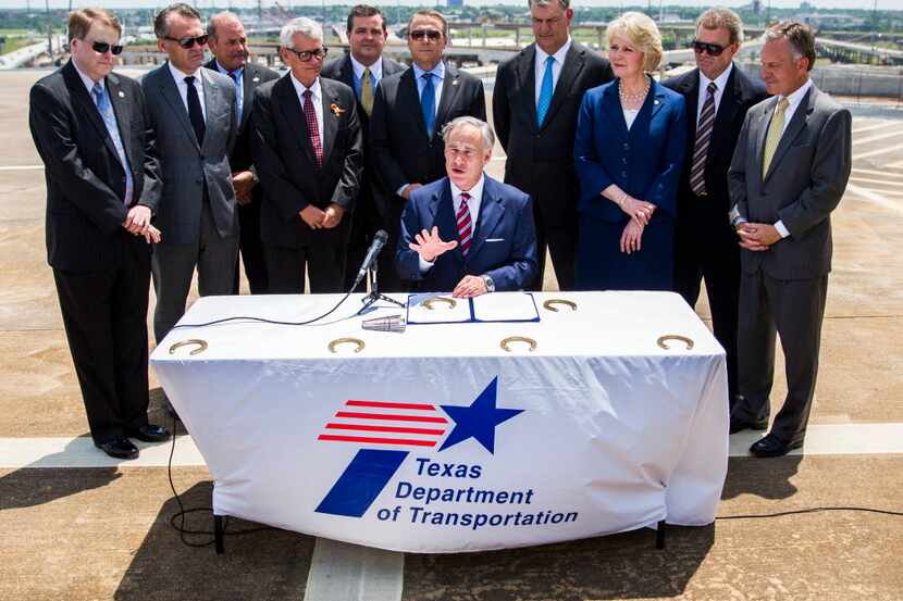  Governor Greg Abbott signs a transportation funding bill surrounded by legislators, Dallas...