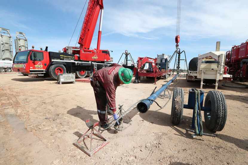 Halliburton employees work at a three-wellhead fracking site in Midland. (Steve...
