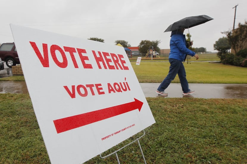A voter uses an umbrella as she enters the polling place to vote at the United Memorial...