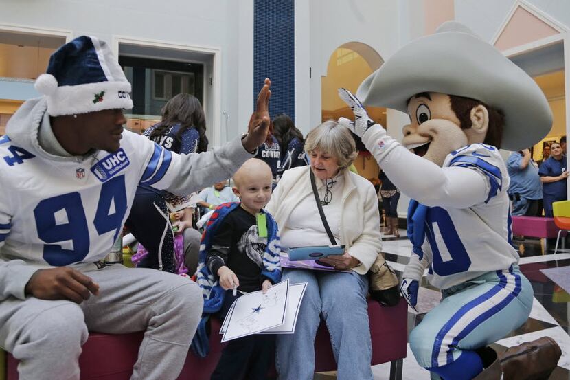 Dallas Cowboys defensive end Randy Gregory and Rowdy, the Cowboys mascot, high five while...