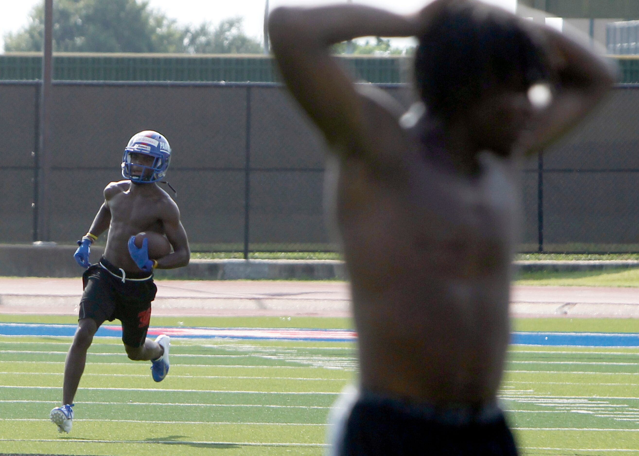 A Duncanville Panther varsity player returns a kick during a drill as a teammate stretches...