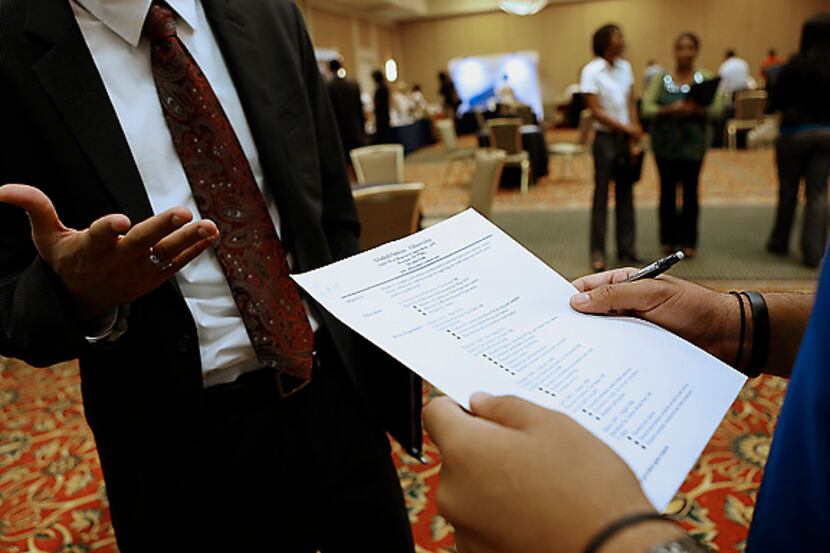 A recruiter, right, reviews a job seeker's resume during a Coast to Coast Career Fairs event...