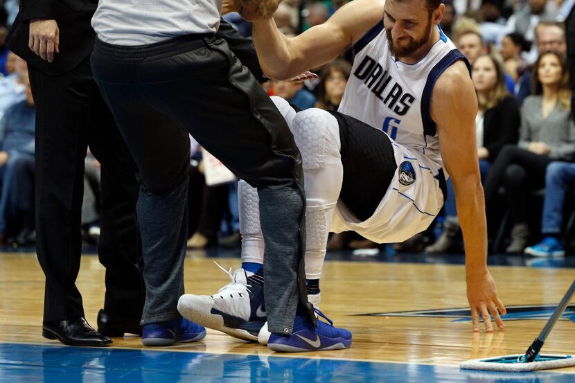 Mavericks center Andrew Bogut is helped up after hyperextending his knee on Monday. He is...