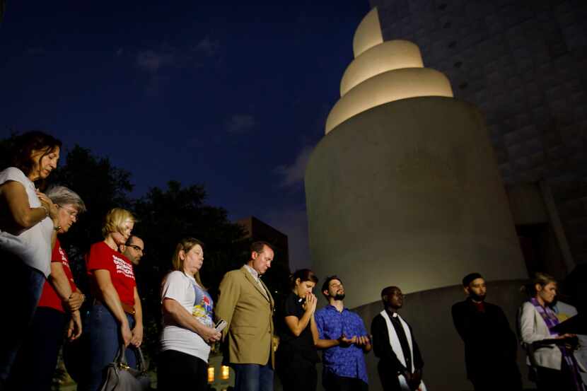 Activists, elected officials and faith leaders observe a moment of silence during a vigil at...