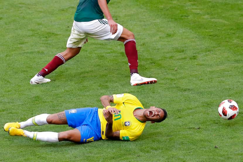El delantero de Brasil Neymar se desploma en el césped ante el defensor de México Edson...
