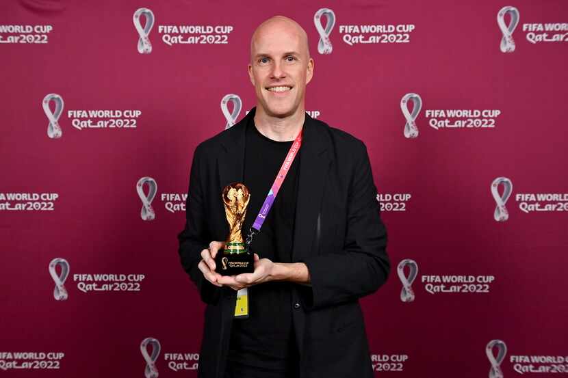 Grant Wahl smiles as he holds a World Cup replica trophy during an award ceremony in Doha,...