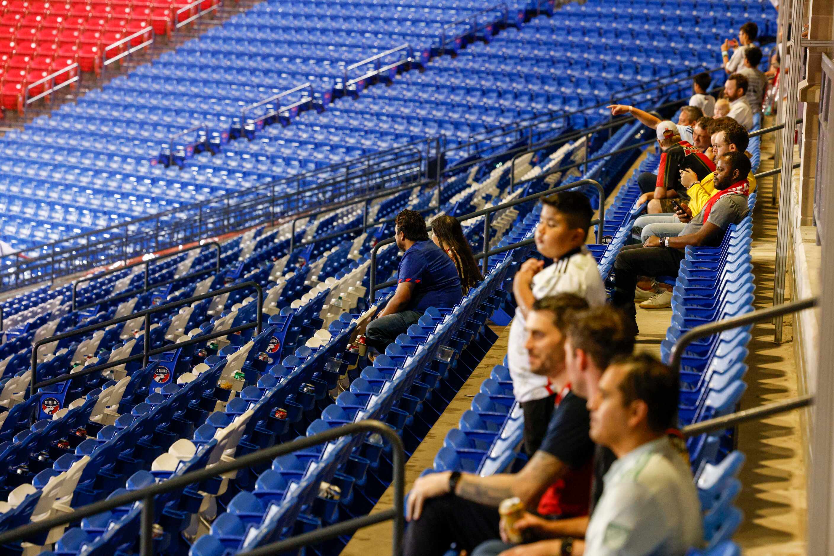 Fans sit under an awning during a lightning delay before an MLS game between FC Dallas and...