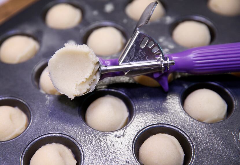 Use a cookie scoop to fill mini muffin pans with dough.