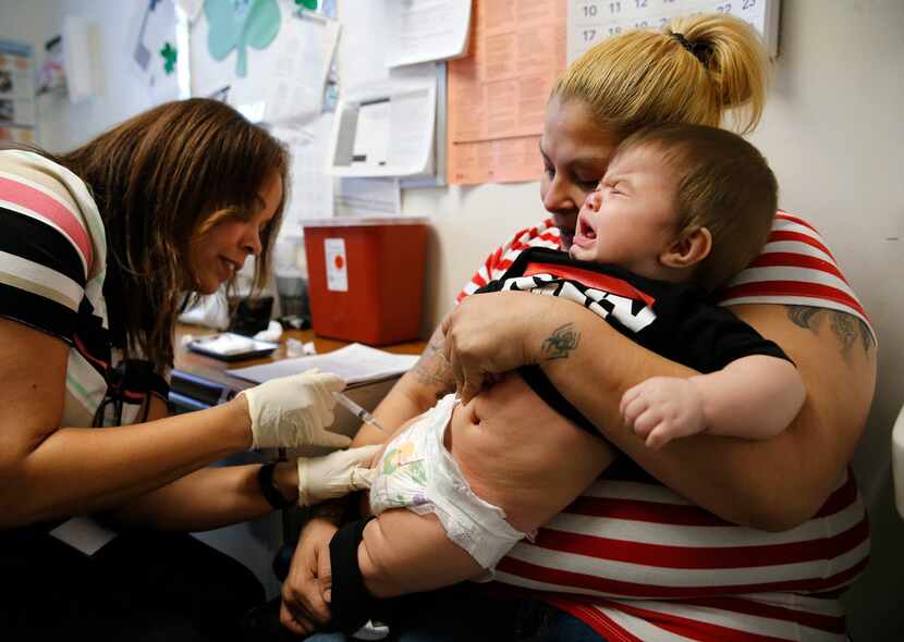 Eight-month-old Rambo Islas cries as he is held by his mother Maria Islas, who watches as...