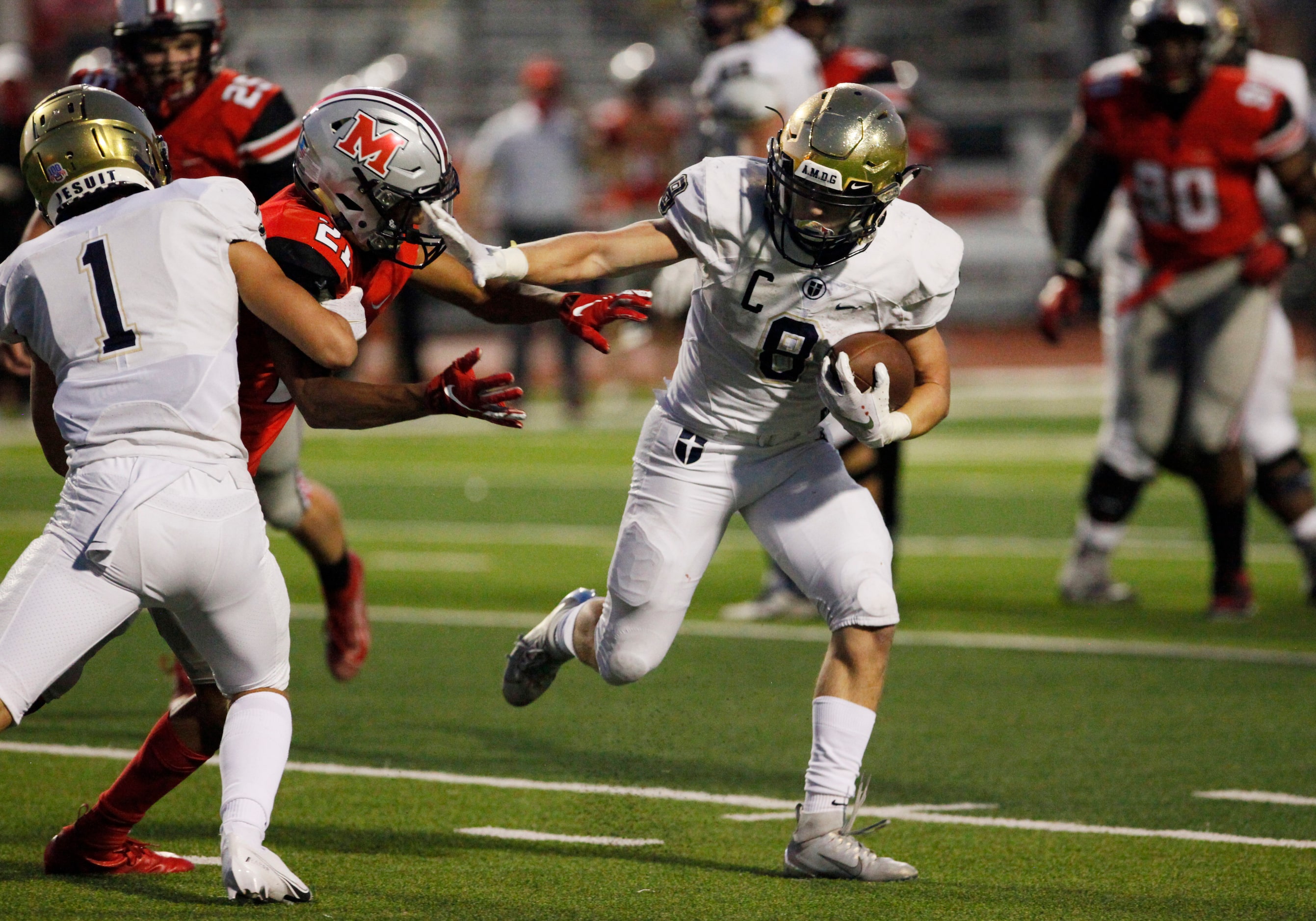 Jesuit senior running back Jake Taylor (8) stiff arms Flower Mound Marcus sophomore Zach...