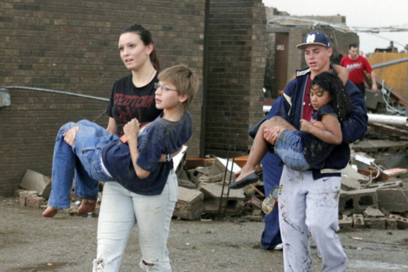 Teachers carry children away from Briarwood Elementary school after a tornado destroyed the...