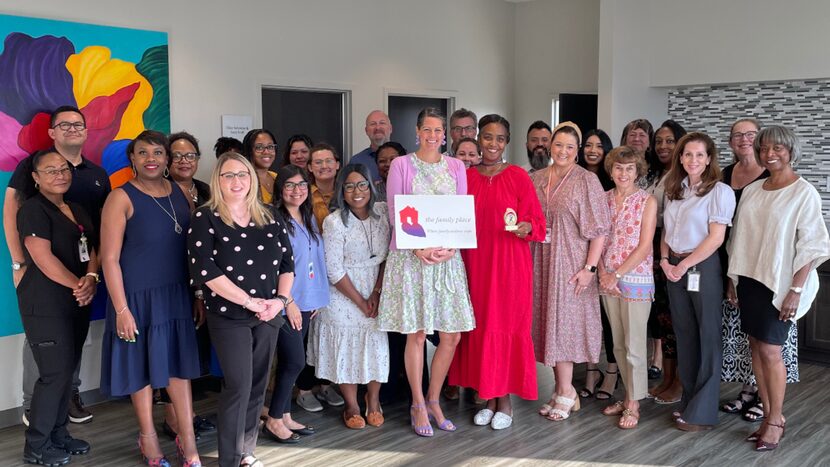 Mimi Sterling, CEO of The Family Place, is pictured with staff and is holding a sign saying...