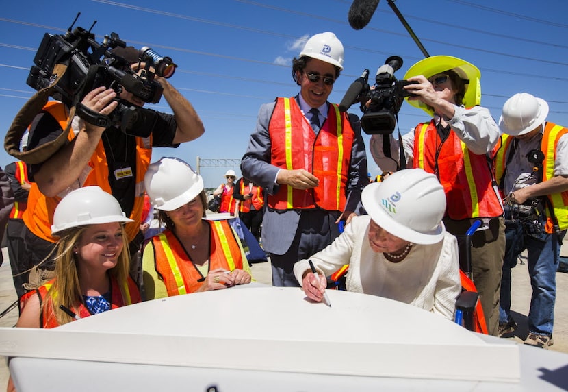 Margaret McDermott, right, signs a piece of the Margaret McDermott Bridge, which was named...