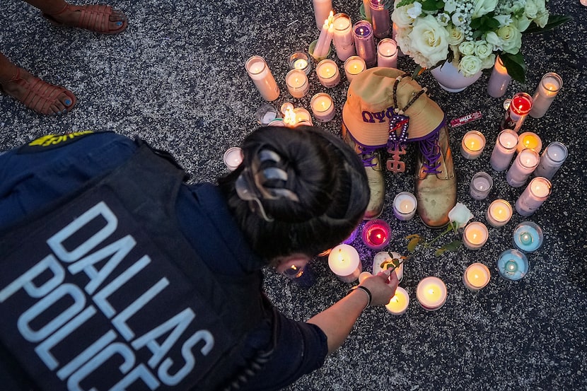 A Dallas police officer places a flower on a memorial surrounding his fraternity boots...