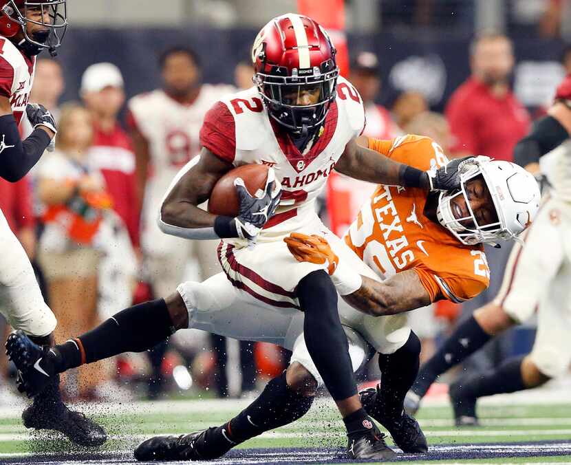 Oklahoma Sooners punt returner CeeDee Lamb (2) stiff arms Texas Longhorns Josh Thompson (29)...