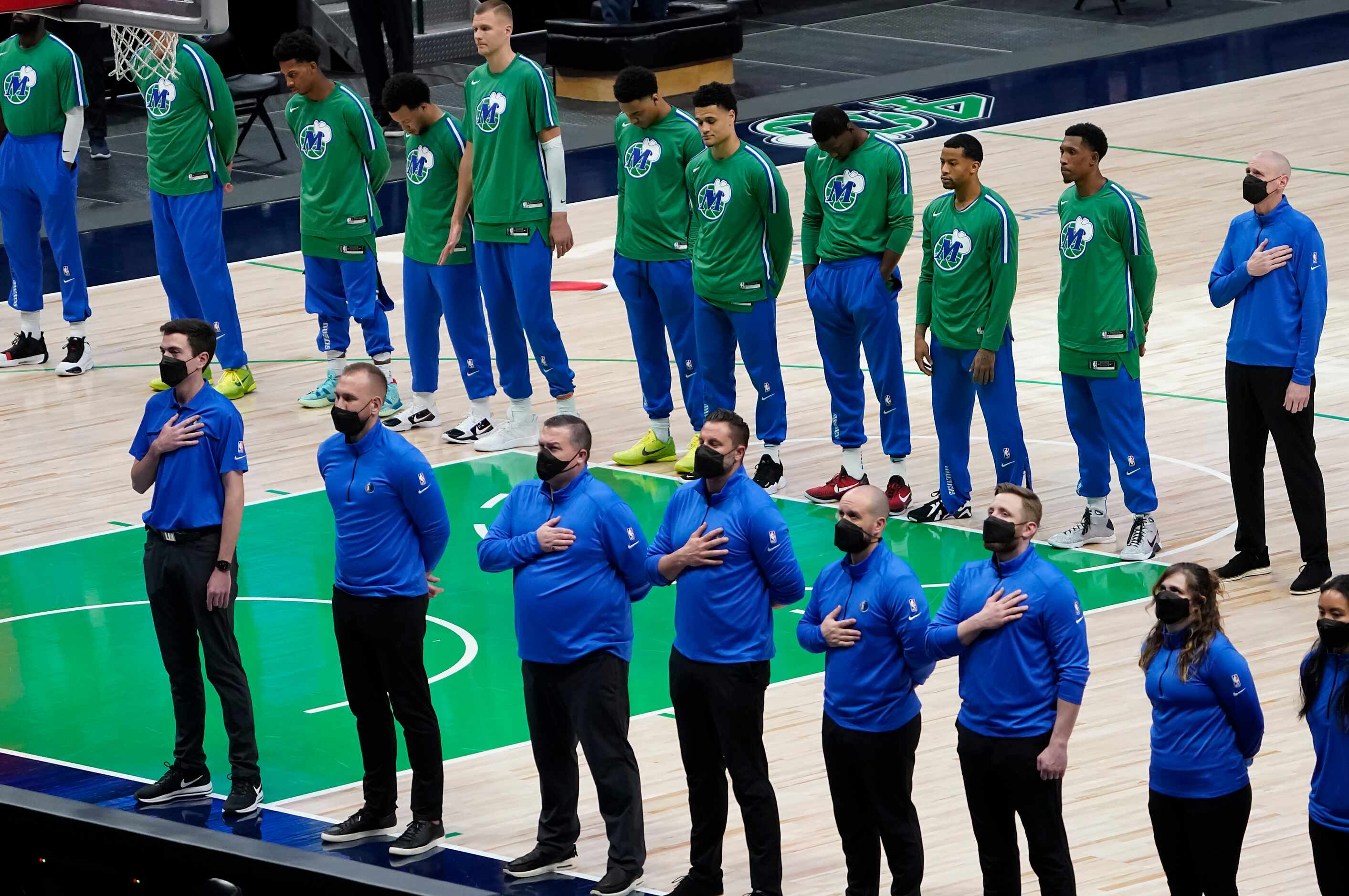 Dallas Mavericks players and staff stand for the national anthem before an NBA basketball...