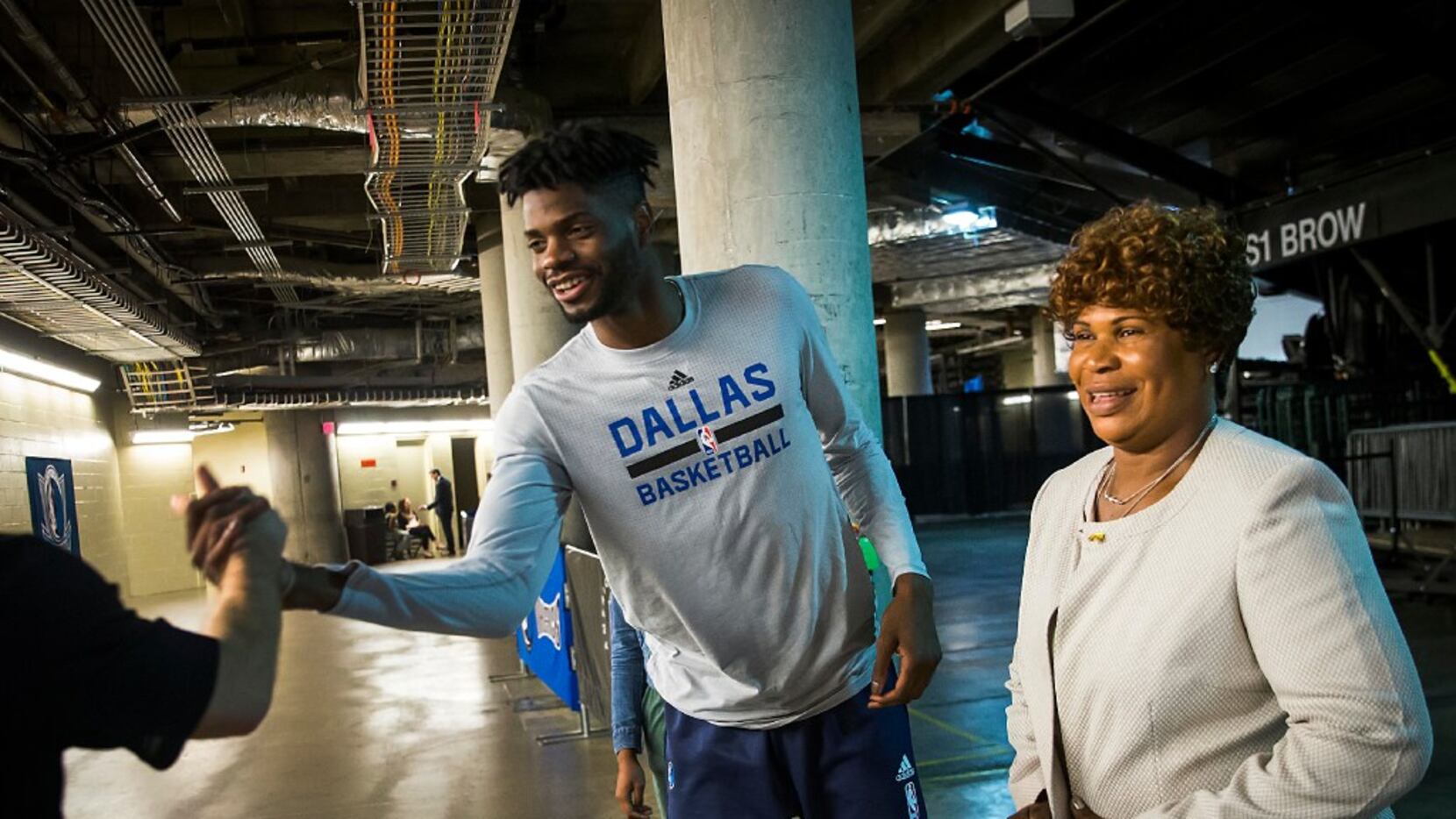 Dallas Mavericks forward Nerlens Noel shakes hands with a fan in the tunnel with his mother...