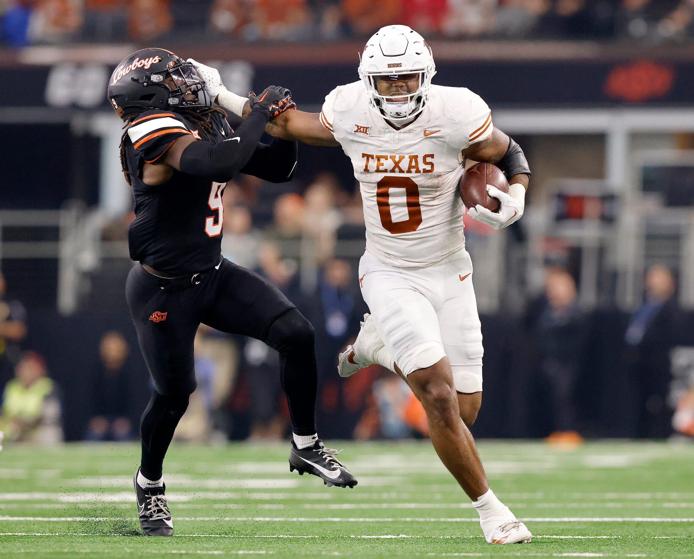 Texas Longhorns tight end Ja'Tavion Sanders (0) gives a stiff arm to Oklahoma State Cowboys...