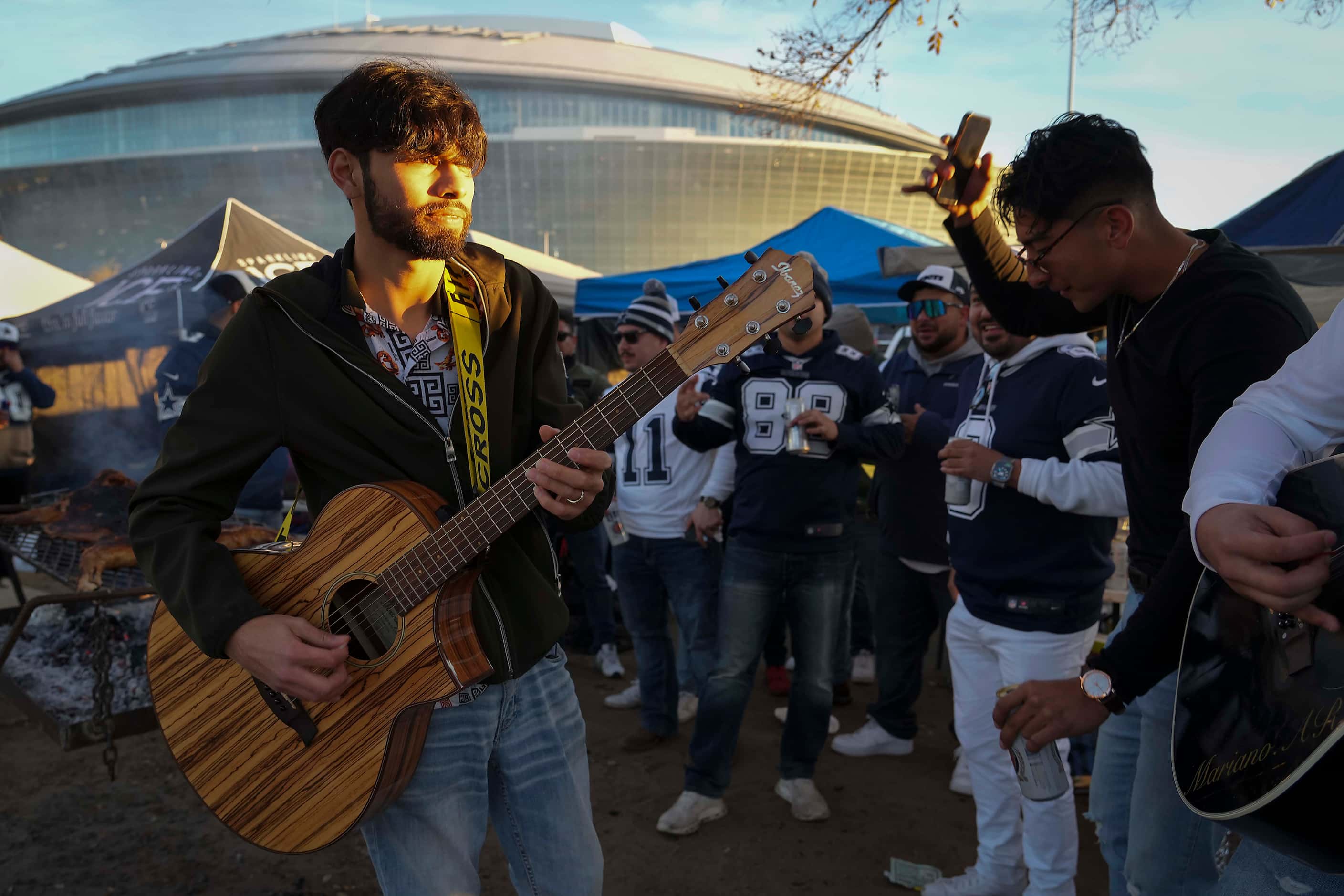 Junior Hernandez of Grupo HZ plays guitar as fans tailgate before an NFL football game...