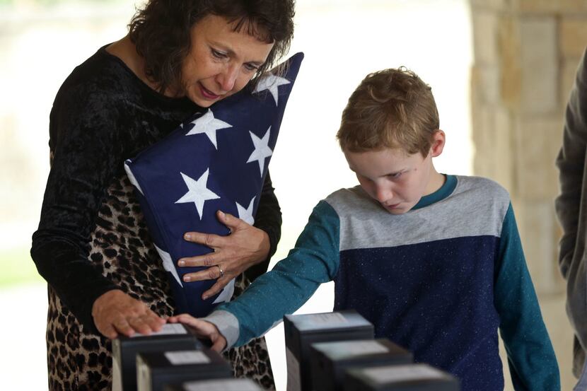Suzy Robinson and her grandson Hayden Robinson touch the box containing the remains of her...