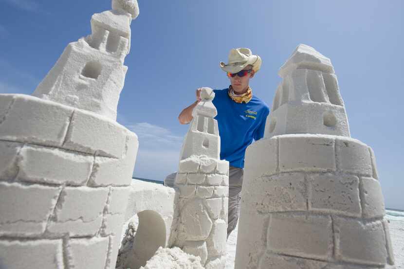 Casey Fabianski with Beach Sand Sculptures puts the finishing touches on a sand castle at...