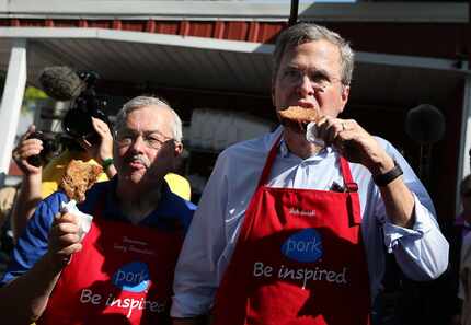 Former Florida Gov. Jeb Bush and then-Iowa Gov. Terry Branstad eat pork chop on a stick at...