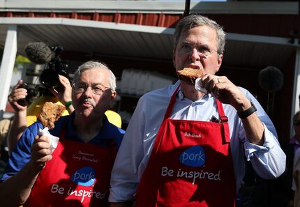 Former Florida Gov. Jeb Bush and then-Iowa Gov. Terry Branstad eat pork chop on a stick at...