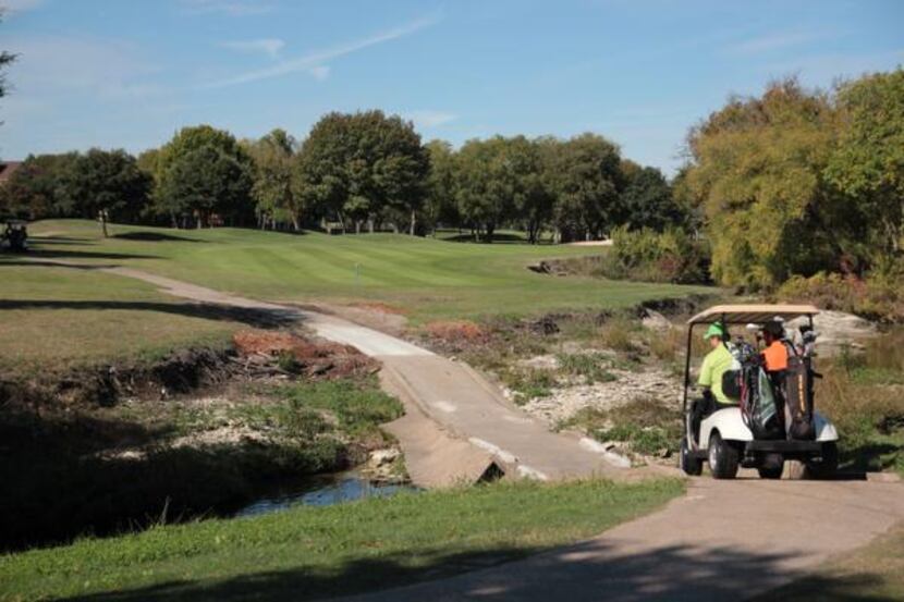 Rick and Lucas Moffitt drive the cart path on the third hole of Duck Creek Golf Club.