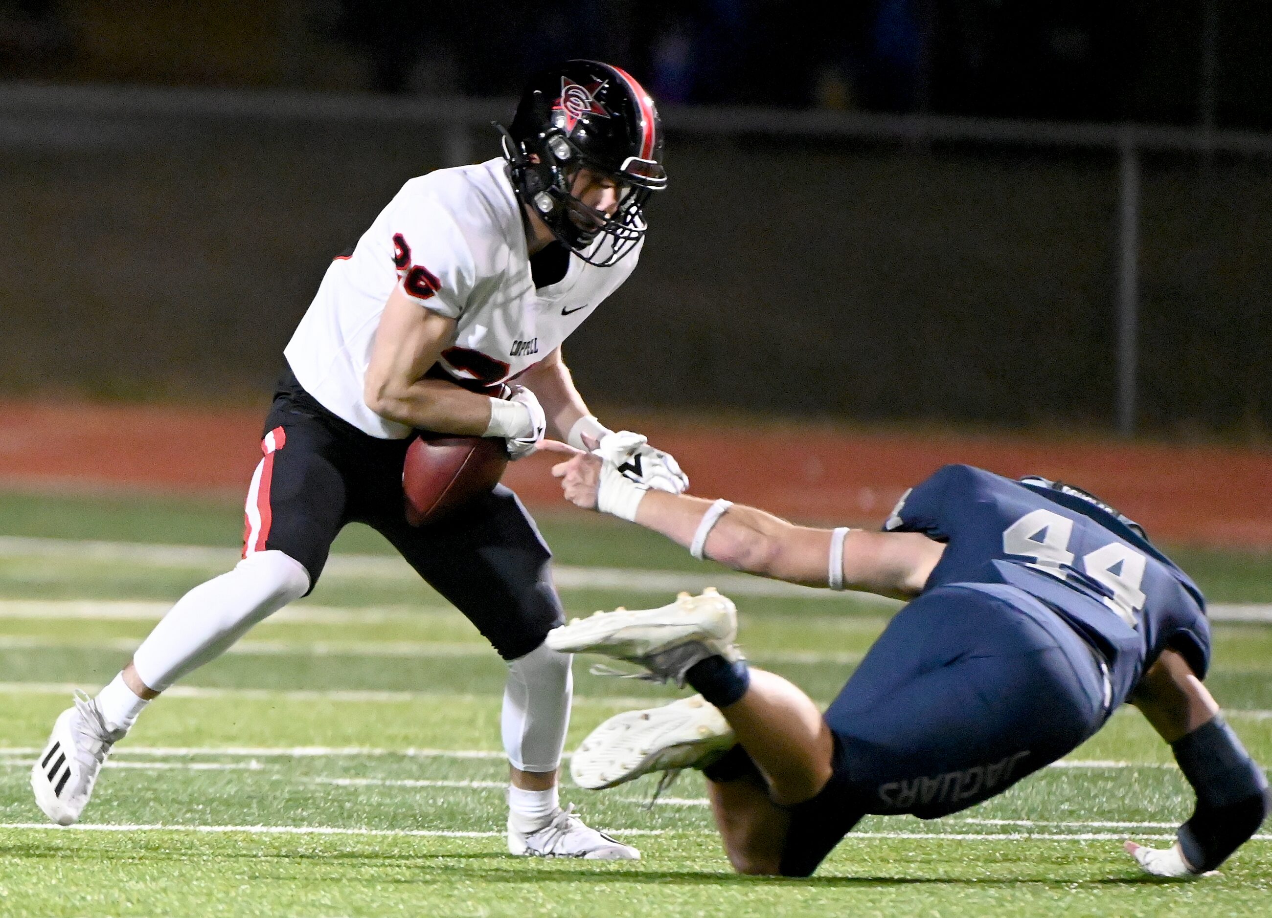 Coppell's Zack Darkoch (26) runs past a tackle attempt by Flower Mound's Ryan Brubaker (44)...